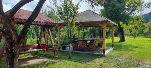 a wooden gazebo with a picnic table in a park at Casa Arabela in Vişeu de Sus