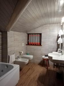 uma casa de banho com 2 lavatórios, uma banheira e um WC. em Hotel Astoria em Courmayeur