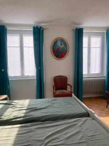 a bedroom with a bed with blue curtains and a chair at TANGO appartement de charme calme lumineux 75m2 6 personnes in Mulhouse