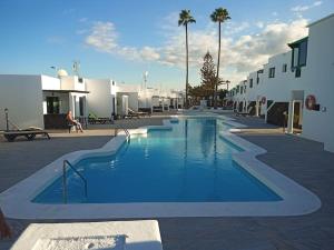 a large blue swimming pool in a courtyard with buildings at Casa Su, precioso apartamento en complejo con piscina in Puerto del Carmen