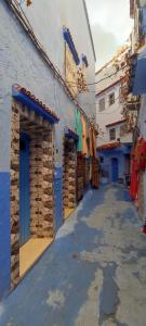 een smal steegje met blauwe deuren en een winkel bij Casa Lotfi in Chefchaouene