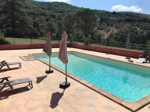 a swimming pool with umbrellas on a patio at Le Cèdre de Prades 4 étoiles Logement entier Parc Naturel Haut Languedoc - Salagou in Dio-et-Valquières