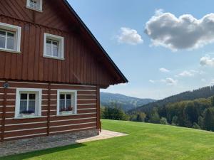 een huis op een heuvel met een groen veld bij Mezi Kopci - Mid Hills House - Dům s výhledem na sjezdovky in Vítkovice