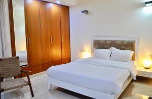 um quarto com uma grande cama branca e uma cadeira em Aashianaa Gracious Living em Nova Deli