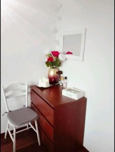 un escritorio con un jarrón de flores y una silla en Zaspa Apartament, en Gdansk