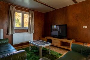 uma sala de estar com uma televisão, um sofá e uma mesa em TIRAMISU Vendégház em Csókakő