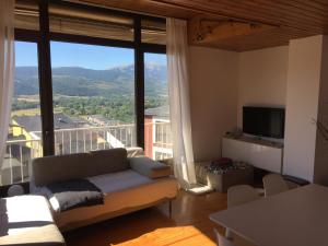 ein Wohnzimmer mit einem Sofa und einem großen Fenster in der Unterkunft Apartamento en Puigcerda in Puigcerdà