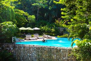 a swimming pool with couches and umbrellas at Hotel La Aldea del Halach Huinic in Palenque