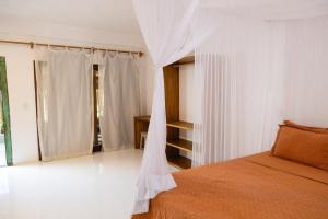 a bedroom with a bed with a mosquito net at Pousada Casa Marae - beira mar in Caraíva +97 photos