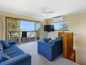 a living room with two blue couches and a flat screen tv at Breeze on Scenic - 7 Scenic Way, Carrickalinga in Carrickalinga