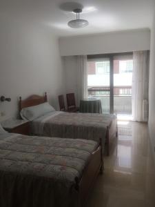 Habitación de hotel con 2 camas y ventana en RESIDENCIA UNIVERSIDAD, en Ourense