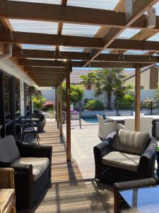 a patio with couches and tables and a wooden pergola at Cromwell Getaway in Cromwell
