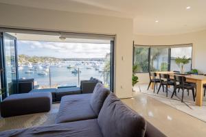 een woonkamer met een bank en uitzicht op een haven bij LUXURIOUS BEACH FRONT APARTMENT cronulla in Burraneer