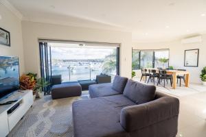 een woonkamer met een bank en een televisie bij LUXURIOUS BEACH FRONT APARTMENT cronulla in Burraneer