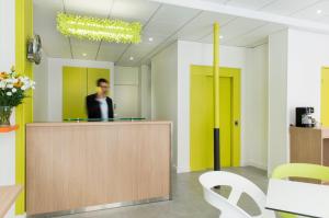 a man standing at a counter in an office at Hotel Bel Oranger Gare de Lyon in Paris