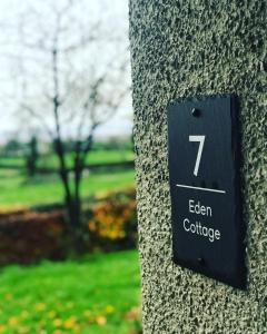 un cartello sul lato di un muro di pietra di Eden Cottage a Lisburn