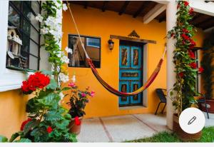 a yellow house with a red door and flowers at ITCHIMBIA GARDEN con la mejor vista de Quito y SPA in Quito