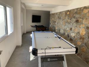 a ping pong table in a room with a stone wall at La Villa de Almudena in Acapulco