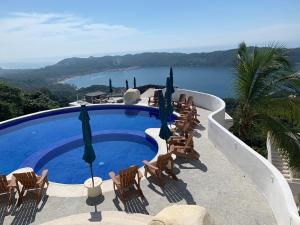 a swimming pool with chairs and umbrellas and the ocean at La Villa de Almudena in Acapulco
