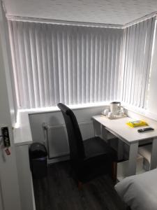 a desk with a chair next to a window with blinds at Glorious BnB Longbridge in Longbridge