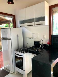 uma cozinha com electrodomésticos brancos e uma bancada preta em Casa 2 Suítes com Ar, Piscina a 400 mts Praia - Taipu de Fora Barra Grande #3 em Maraú