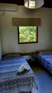 um quarto com duas camas e uma janela em Casa 2 Suítes com Ar, Piscina a 400 mts Praia - Taipu de Fora Barra Grande #3 em Maraú