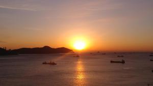 una puesta de sol sobre el océano con barcos en el agua en Brown-Dot Hotel Songdo, en Busan