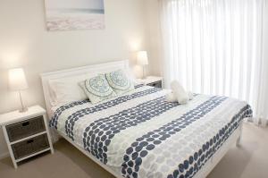 a bedroom with a bed with a teddy bear on it at Rolling Waves 1 in Merimbula