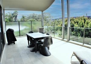 Habitación con balcón con mesa y sillas. en Rolling Waves 1, en Merimbula
