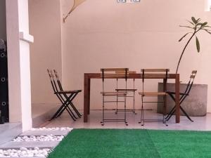 comedor con mesa, sillas y alfombra verde en Pinang Beach Cottage @ Ferringhi, en Batu Ferringhi
