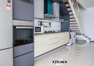 een keuken met roestvrijstalen apparatuur en een trap bij Rumahku Gurney with 270 degree Sea View in George Town