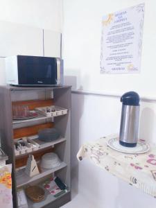 a kitchen with a microwave and a shelf with food at SUITES COR DO SOL TRINDADE in Trindade
