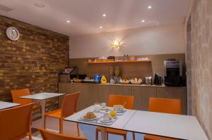 a dining room with a table and chairs and a kitchen at Hotel Bel Oranger Gare de Lyon in Paris