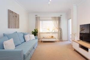 a living room with a blue couch and a tv at Arcadia Apartment - Cottesloe in Perth