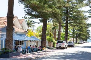 a group of people sitting at tables outside a building at Arcadia Apartment - Cottesloe in Perth