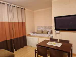 sala de estar con mesa, TV y sofá en BUENAVISTA PREMIUM, en Sierra Nevada