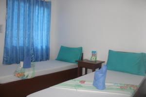 two beds in a room with blue curtains at Love Vega Hometel in El Nido