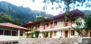 a building with a balcony and mountains in the background at Hotel Garden House Huerta in Limatambo