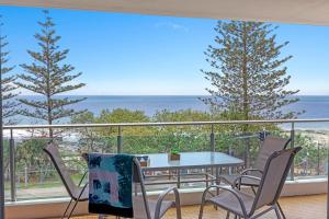 uma varanda com uma mesa e cadeiras e o oceano em Northwind Beachfront Apartments em Mooloolaba