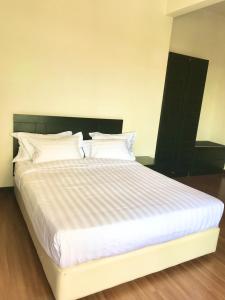 1 dormitorio con 1 cama grande con sábanas y almohadas blancas en Taman Air Lagoon Resort at A921, unlimited waterpark access, Melaka en Melaka
