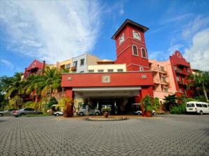 ein rotes Gebäude mit einem Uhrturm auf einem Parkplatz in der Unterkunft 2 room Apartment @ Langkawi Lagoon Resort in Kampung Padang Masirat