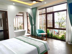 a bedroom with a bed and a chair and windows at Lasol Boutique Hotel in Da Lat