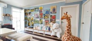 um quarto com uma girafa e animais de peluche numa prateleira em Hago Guest House em Tongyeong