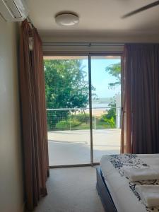 a bedroom with a bed and a large glass window at Beachfront Beauty! in Mission Beach