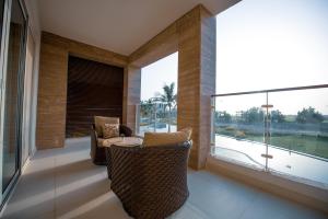 a balcony with a table and chairs and a large window at Jebel Sifah studio Apartment with Sea & Pool View in As Sīfah