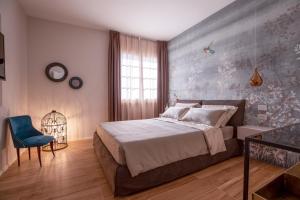 een slaapkamer met een groot bed en een blauwe stoel bij Villa Elia Suite Room in Bellaria-Igea Marina