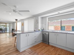 a kitchen with white cabinets and a large window at Alka Beach House in Callala Beach