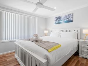 a white bedroom with a large white bed and a window at Alka Beach House in Callala Beach