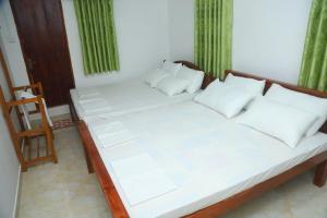 a bed with white sheets and pillows in a room at FOREST VIEW HOME STAY in Anuradhapura