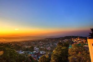 Blick auf eine Stadt bei Sonnenuntergang in der Unterkunft LA Riqueza Bliss Valley Mall Road - Beautiful View of Mountains in Dharamshala